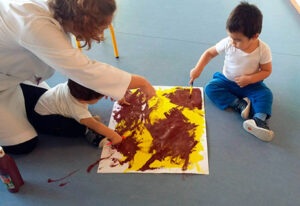 teacher painting with toddlers in a school in Spain