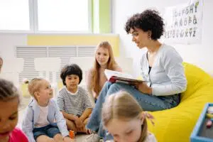 Early Childhood Educator reading a book to a group of toddlers
