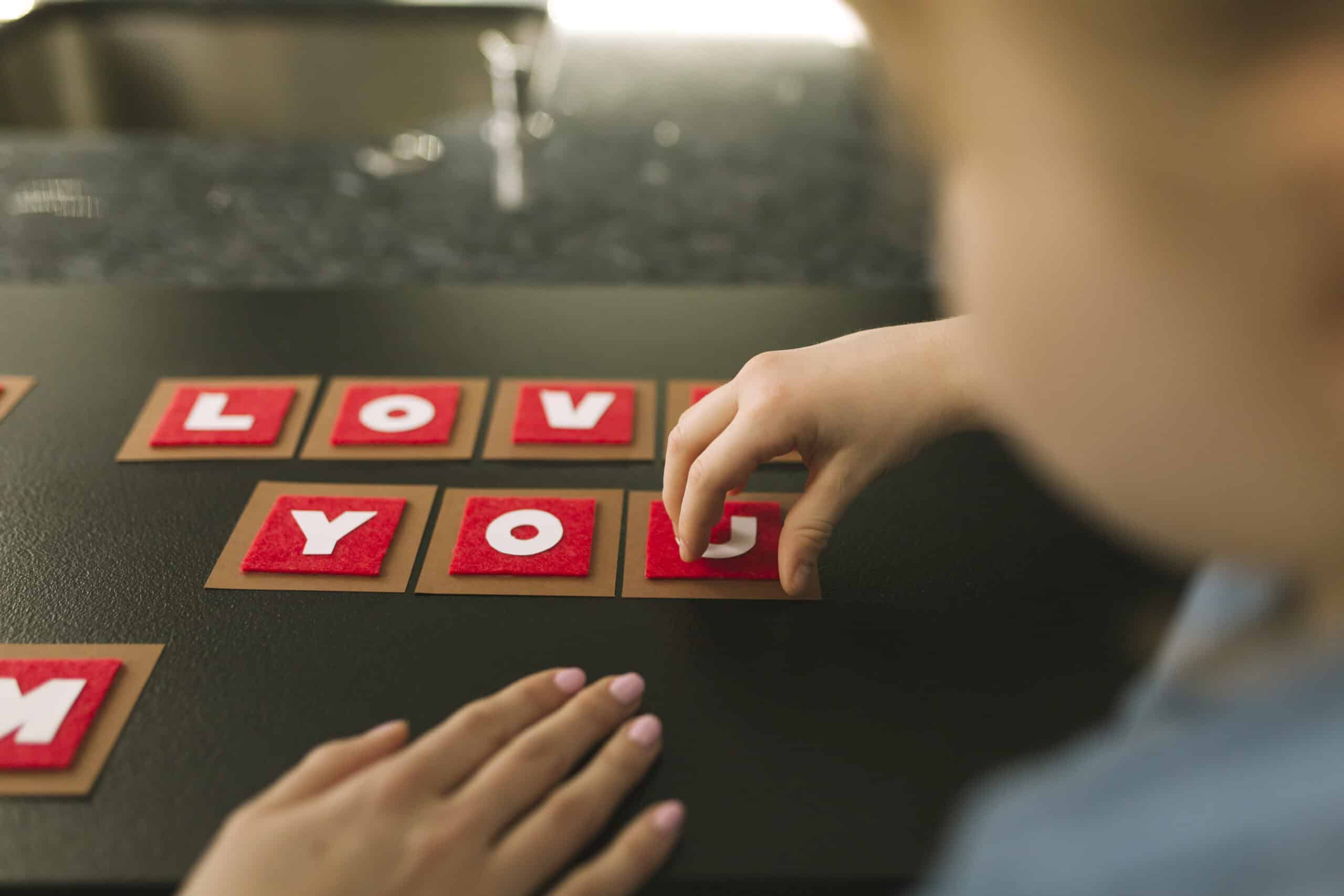 Child playing with letters, spelling out "Love you".